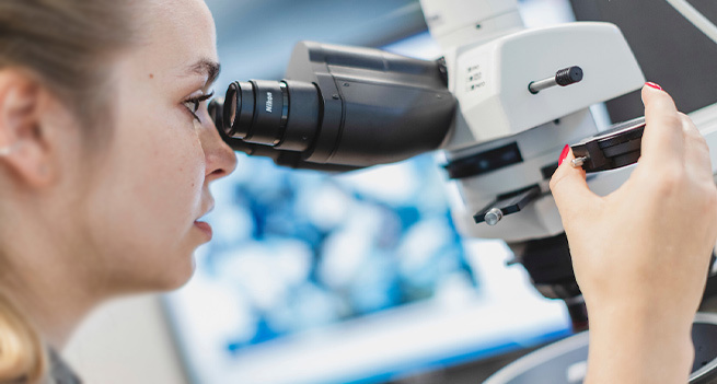 A woman is looking in a microscope