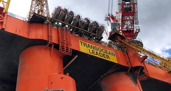 A close-up of an oil rig with a yellow sign that says 'Transocean Leader'